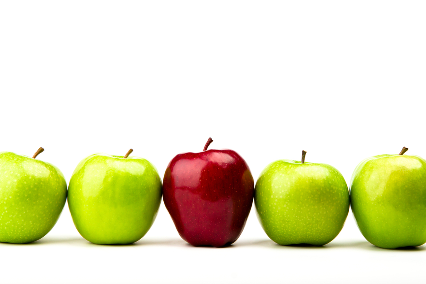 Red apple among green apples isolated on a white